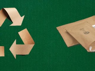 Recycling Zeichen aus Karton auf grünem Grund, daneben Papier-Versandtaschen